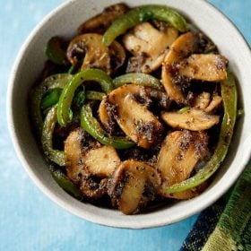 mushroom pepper fry served in a cream colored ceramic bowl with text layover.