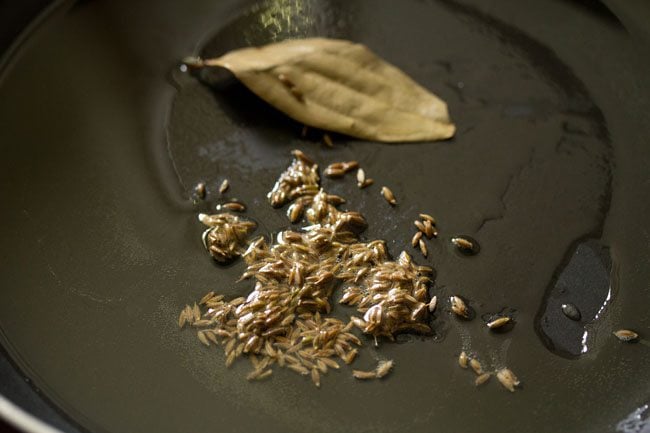 sautéing cumin seeds and tej patta in hot oil in a pan. 
