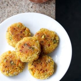 poha cutlet served on a white plate with a bowl of tomato ketchup kept on the top and text layover.