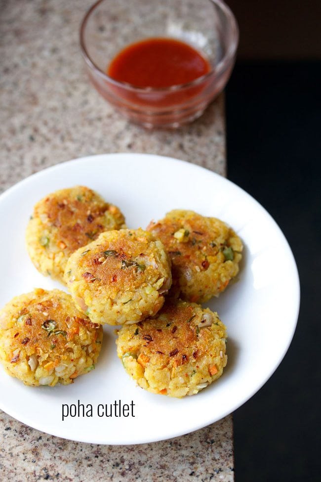 poha cutlet served on a white plate with a bowl of tomato ketchup kept on the top and text layover. 