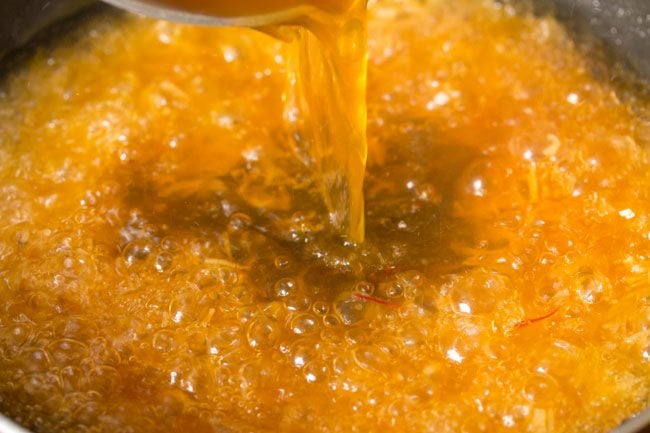 adding hot orange colored sugar solution to the roasted semiya. 