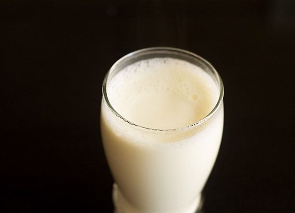 Hot milk is poured into a glass for turmeric milk.