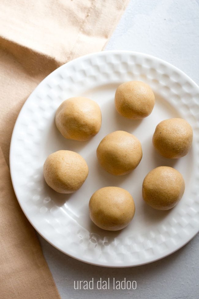 top shot of sunnundalu or urad dal laddu served on a white plate with text layovers. 