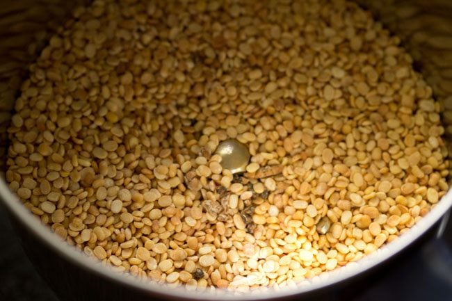 roasted urad dal and cardamom seeds added to a grinder jar. 