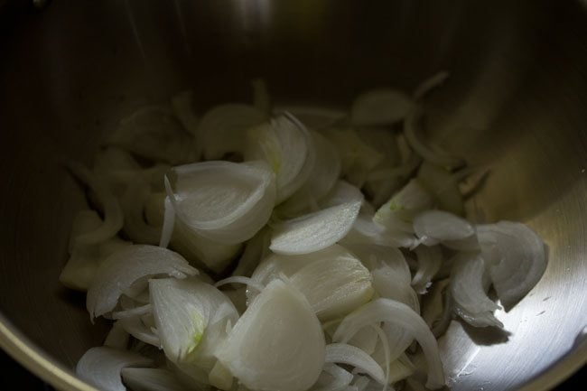 thinly sliced onions added in hot oil in a kadai. 