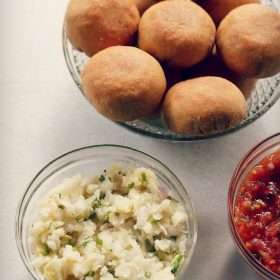 aloo chokha served in a glass bowl with littis in a large bowl and text layover.