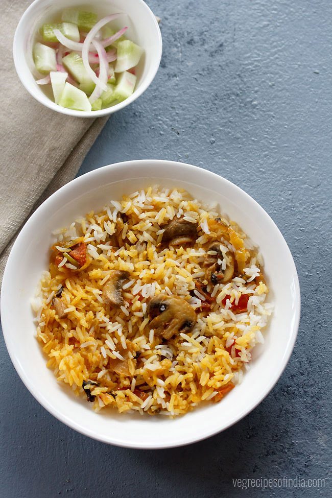 serving Ambur biryani on a plate with a side of vegetable salad