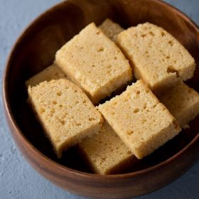 slices of wheat cake kept neatly in a wooden bowl on a light grayish blue board