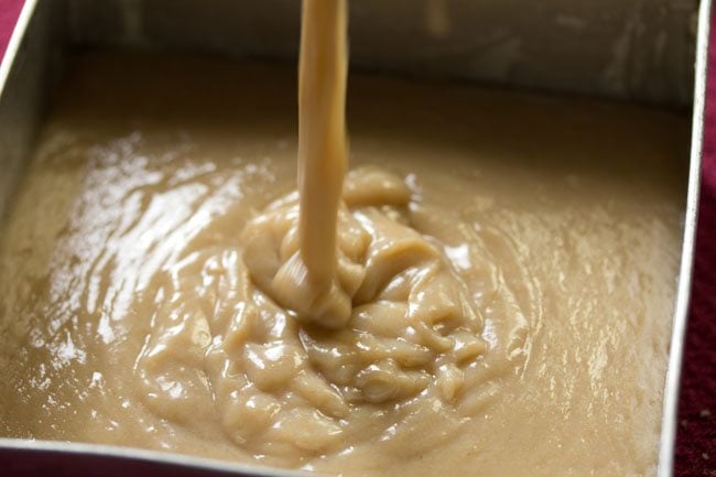 pouring atta cake batter in the greased square pan