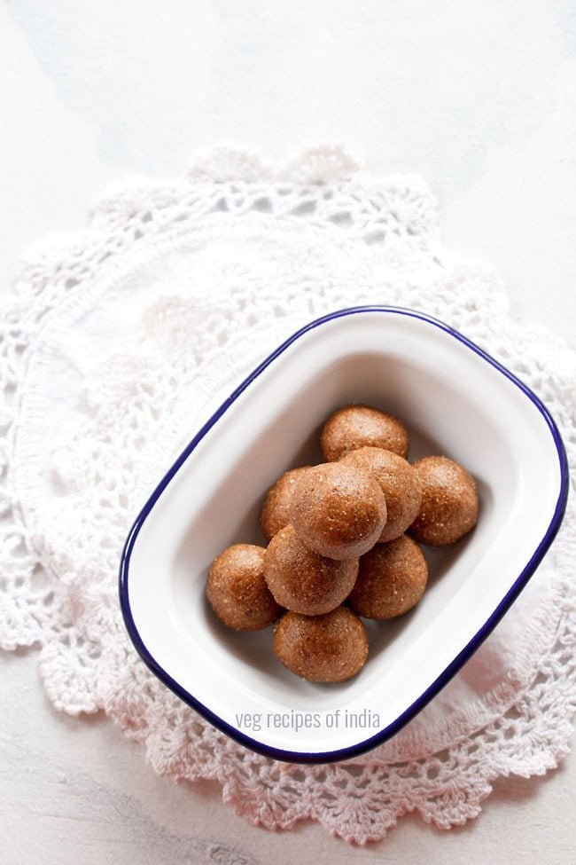 top shot of badam ladoo served in a blue rimmed rectangular shallow plate with text layover. 