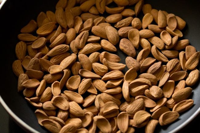 almonds added to hot thick bottomed pan for badam laddu. 