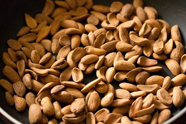 Roast almonds in a pan to make badam ladoo. 