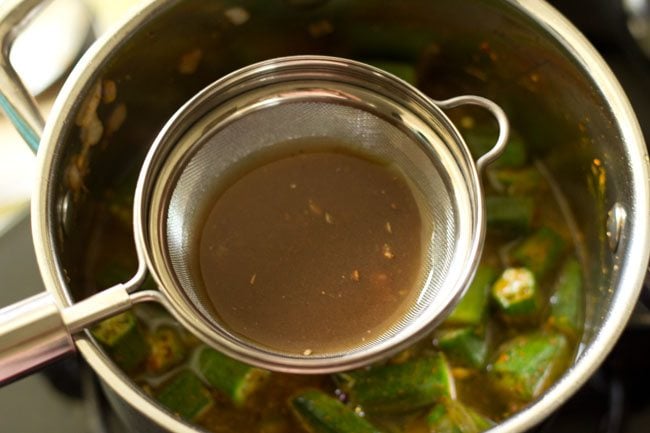 straining tamarind pulp directly into the pan. 