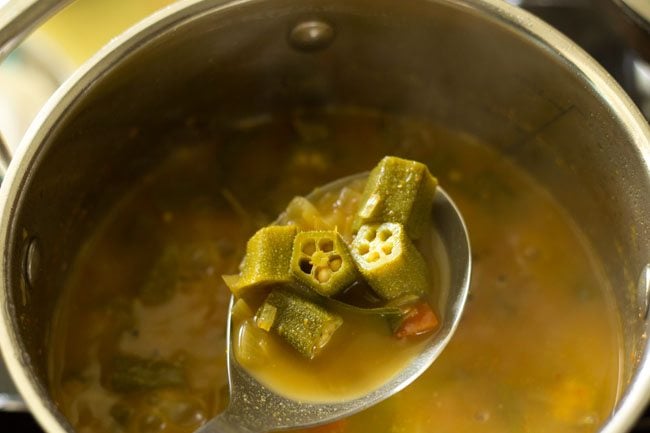 cooked bendakaya pulusu in a spoon. 