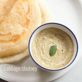 cabbage chutney with a curry leaf in center in a blue rimmed white bowl with two dosa by the side in a white plate
