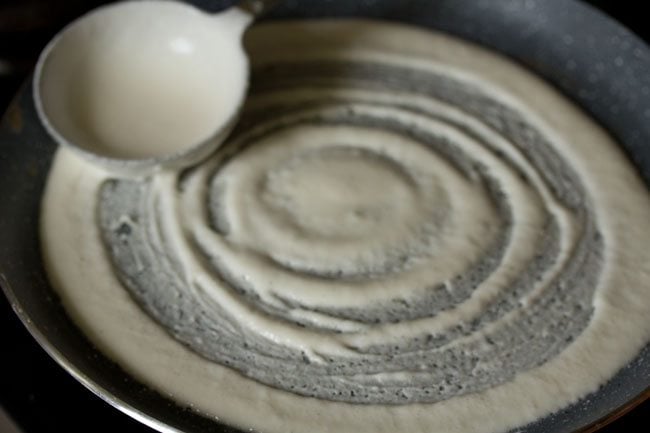 spreading batter on pan to make dosa. 