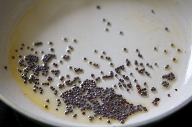 spluttering mustard seeds in hot sesame oil in pan for making tempering. 