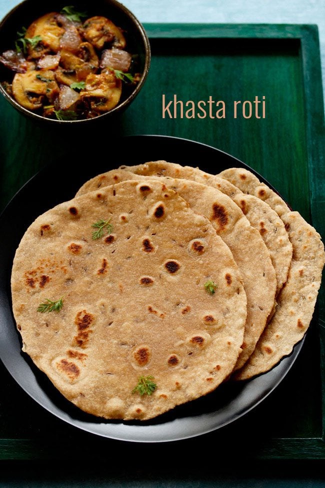 The khasta roti is served on a black plate with a bowl of vegetables in the upper left corner and a text stop.