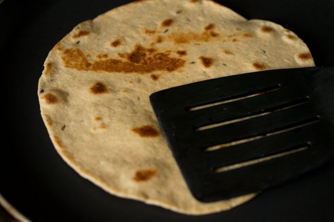 pressing the edges of the roti on the other side. 