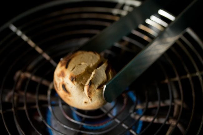 heating litti with the help of tongs to get charred spots on it. 