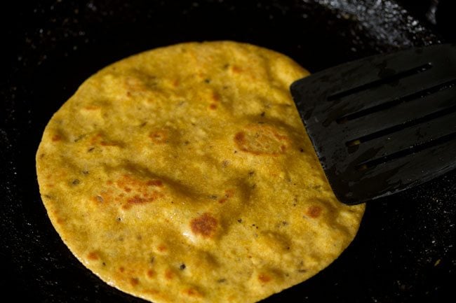 pressing paratha edges with spatula