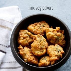 vegetable pakora in a black wooden bowl placed next to a white striped kitchen linen with text layover.