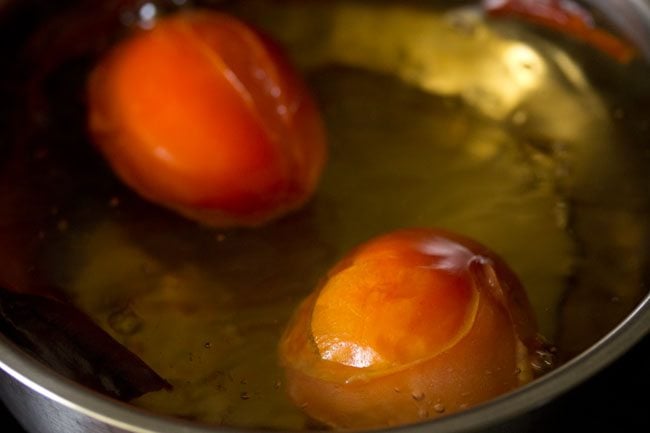 boiling tomatoes and dried red chilies in pan. 