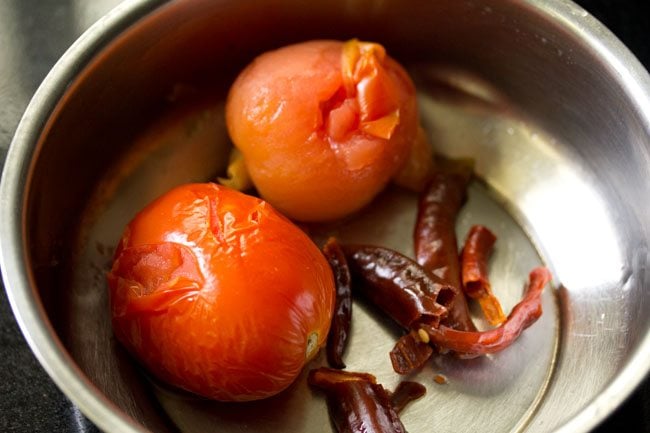 Water strained and tomatoes and dried red chilies getting cooled. 