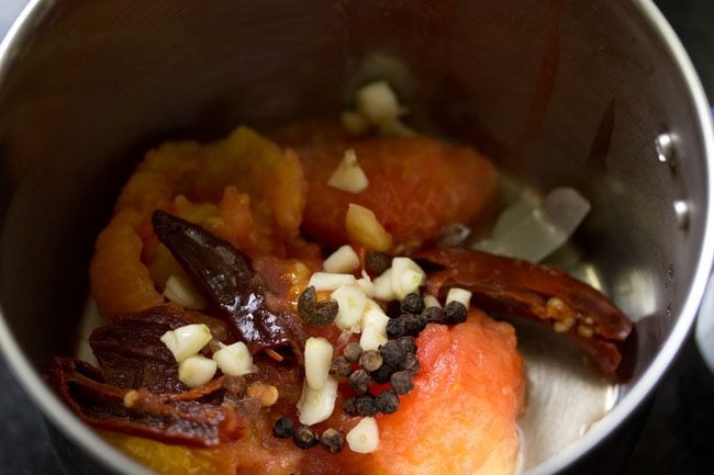 crushed boiled tomatoes, boiled red chilies, chopped garlic, black pepper and Sichuan pepper added in a blender jar.  