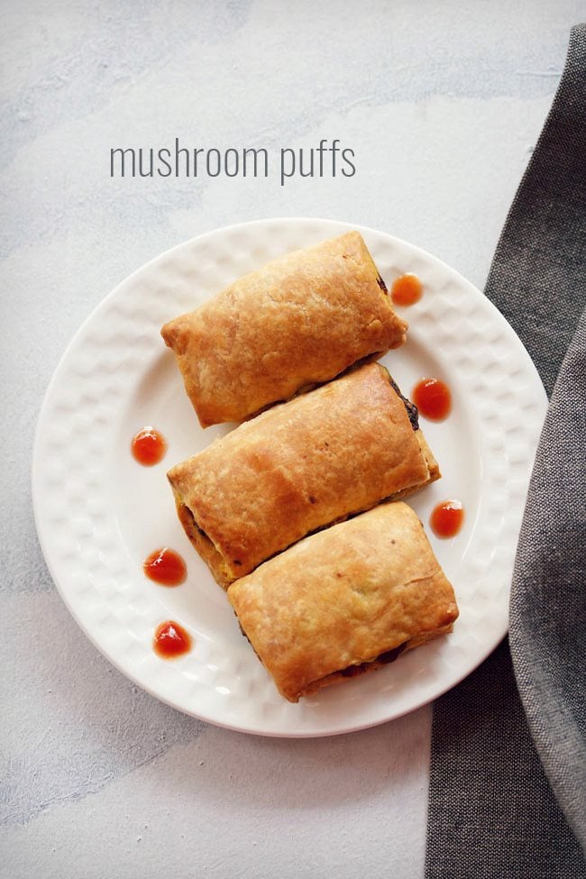 mushroom puff served on a white plate with dots of tomato sauce on the plate and text layover.