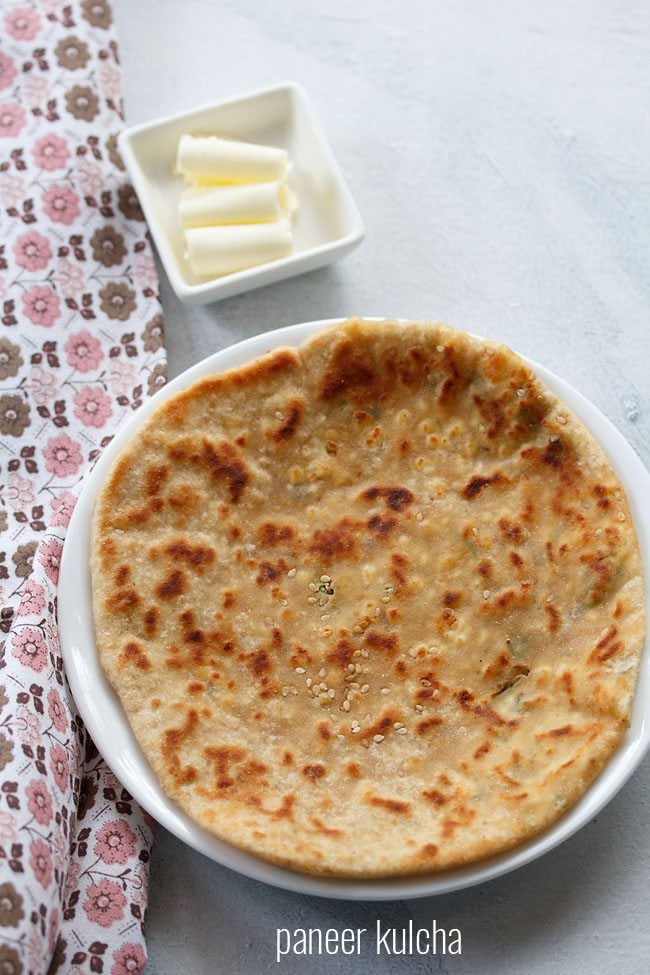 paneer kulcha served on a white plate with a side of butter in a small bowl.