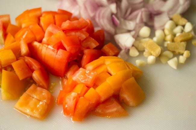 chopped tomatoes, onions, garlic and ginger on a cutting board