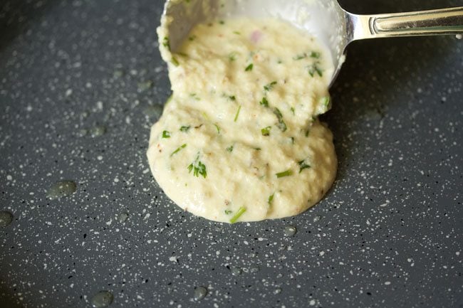 pouring prepared suji ka cheela batter on the pan. 