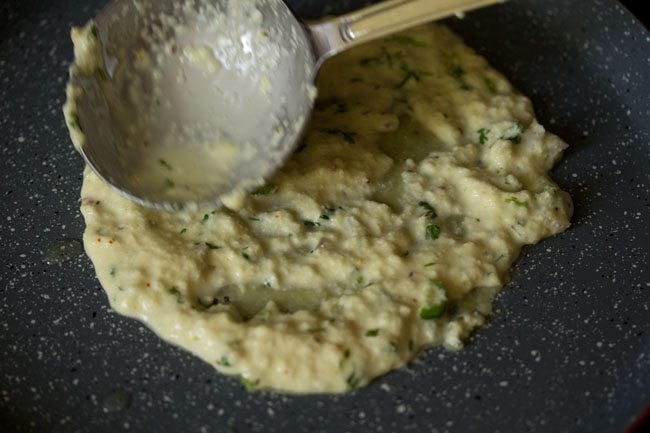 spreading the batter into a round suji ka cheela. 