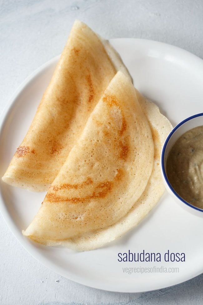 sabudana dosa folded and served on a white plate with a bowl of chutney kept on the left side and text layovers.