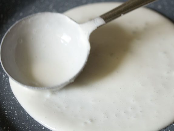 spreading the batter with a ladle into a dosa. 