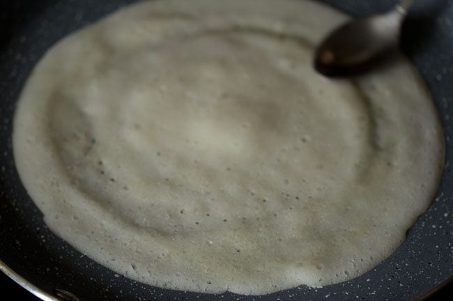 spreading some oil on the cooked top of the sabudana dosa. 