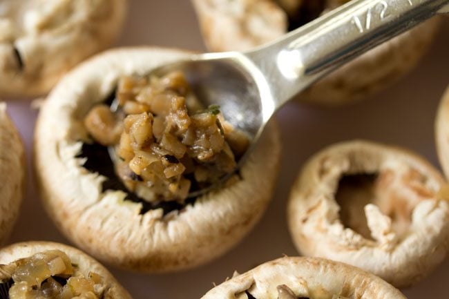 spooning the stuffing in each mushroom cap.