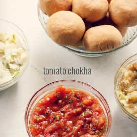 tomato chokha served in a glass bowl with a bowl of litti kept on the top side and text layover.