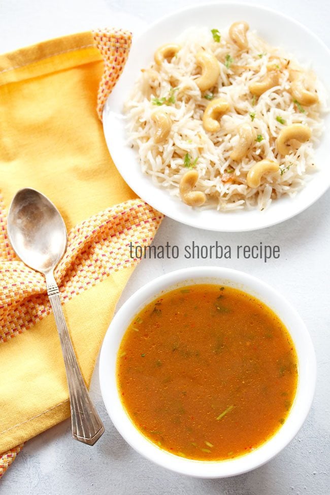 tomato shorba served in a white bowl with a spoon kept on the left side, a bowl of cashew pulao kept on the top right side and text layover.