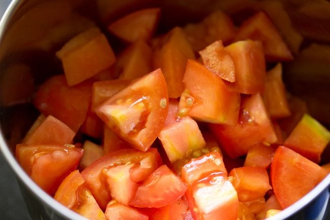 roughly chopped tomatoes added to a blender jar for making tomato dhaniya shorba. 