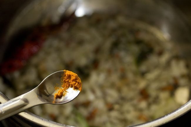 adding turmeric powder to the onion mixture in the pan. 