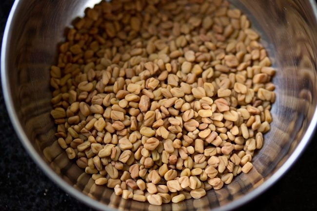 methi seeds added to a bowl for making vendhaya dosa. 