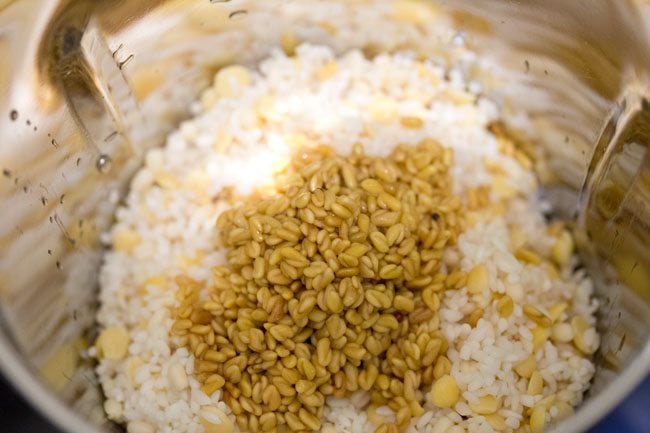 drained rice, lentils and methi seeds added to a wet grinder jar along with water for making batter for vendhaya dosa. 