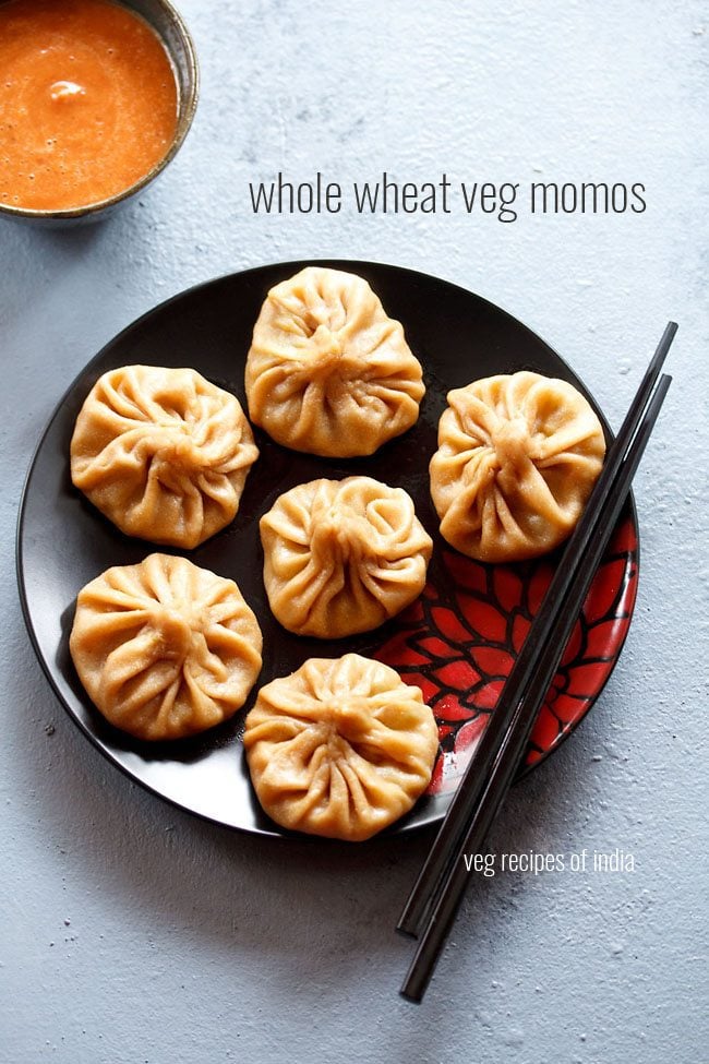 wheat momos arranged on a black plate with black chopsticks kept on the left side with text layovers.