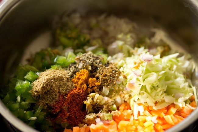 turmeric powder, red chili powder, coriander powder, cumin powder and black pepper powder added to the vegetable mixture in the bowl. 