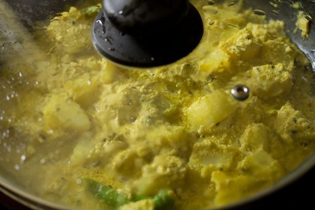 cooking aloo posto in the covered pan. 