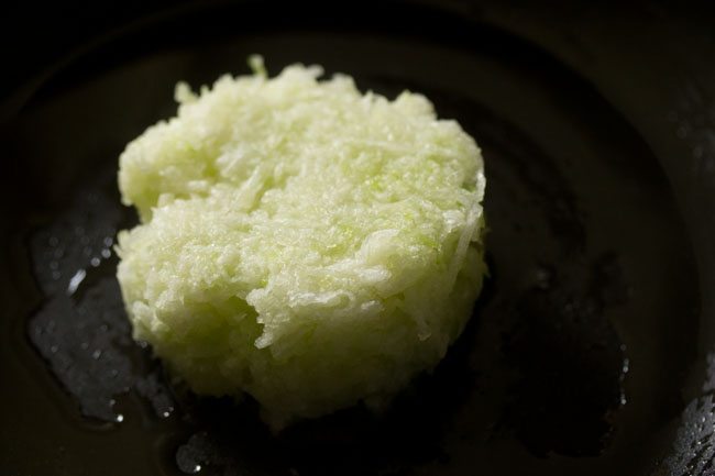 grated ash gourd added in hot ghee for making white pumpkin halwa. 