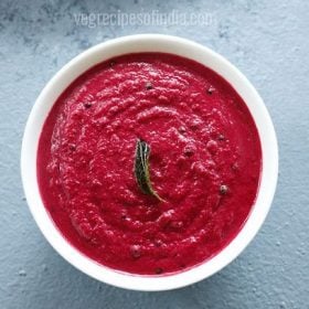 overhead shot of beetroot chutney in white bowl on a light grey blue board