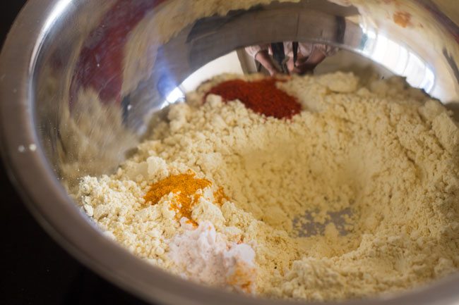 sifted gram flour, turmeric powder, red chili powder and salt added to a mixing bowl for karasev recipe. 